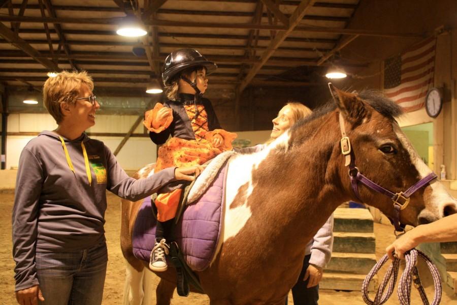 Equestrian therapy is used to treat injuries or handicaps through riding a horse. Nancy Sundh sidewalks with a handicapped child while volunteering at an Equestrian therapy barn. Nancys daughter, Haley Sundh, senior, stands at the same barn with a horse named Scooby.