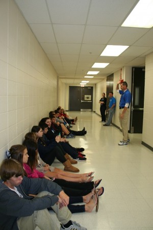 Students sit along the hallway during a severe weather drill. Starting this year, students will now be led into interior classrooms instead of the hallways.