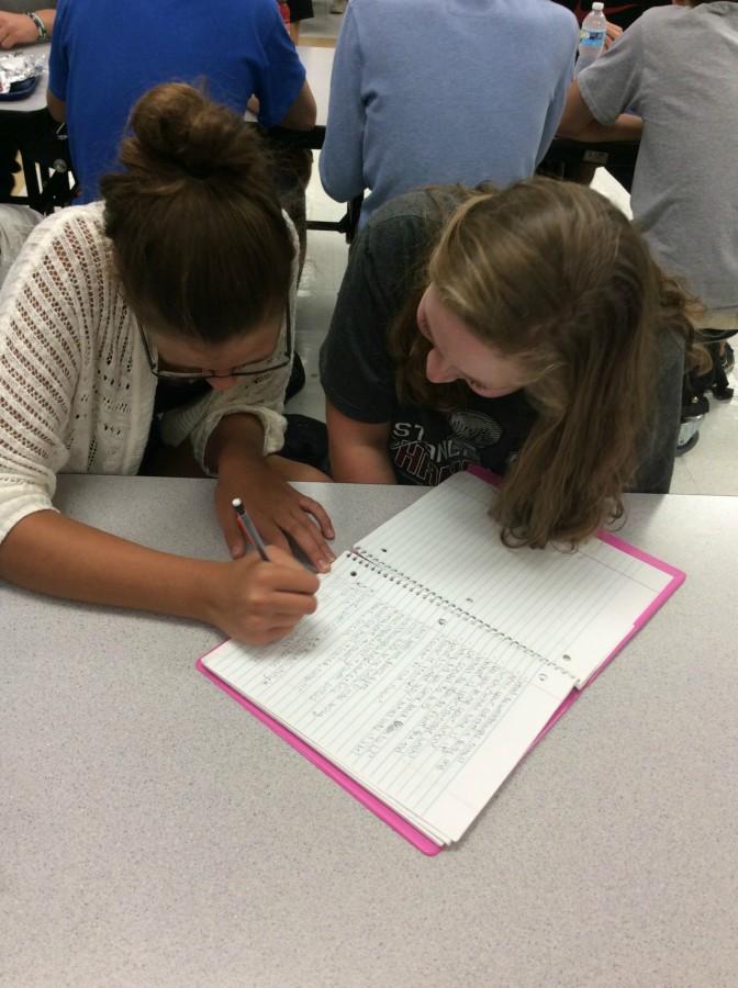 Alyson Wisnionski, freshman, and Jessica Mueller, freshman, hand write their notes rather than using their iPads. Studies show taking longhand notes help students remember the content more than if they use their laptops.