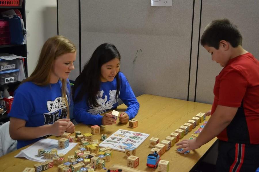 Emma Wenckowski, junior and 16-17 Student Council president, helps students at the Alexander Leigh Center for Autism with Jemma Kim, junior and 16-17 Student Council Vice President. The entire club visited the ALCA to learn about this years charity for charity bash.