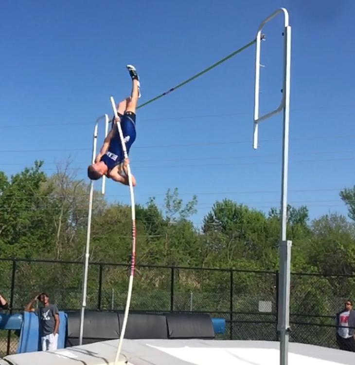 Jake Stevens, junior, hangs in the air as he attempts to clear the bar at a home meet. Stevens broke the school record twice this year, and is working to break it again at State this weekend.