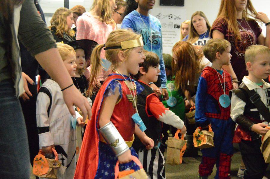 Preschoolers trick-or-treat around the school