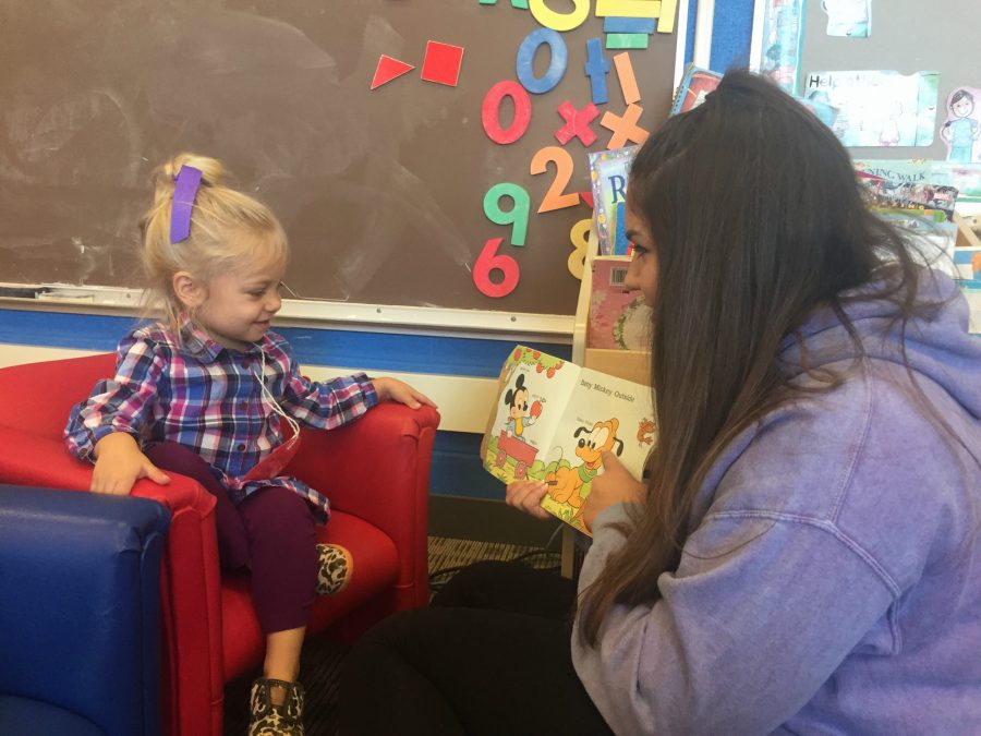 Apollonia Jacobs, preschooler in the child development program, sits and reads with Sydney Shadrick, senior. Jacobs will be aired on TV in a Hillary Clinton commercial.