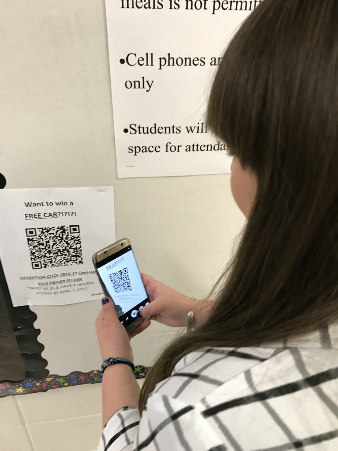 Sarah Shapero, senior, takes a picture of one of the many barcodes on the walls around the school that will take her to where she can sign up for a contest to win a car. She smiles in excitement with the idea of winning a new ride.