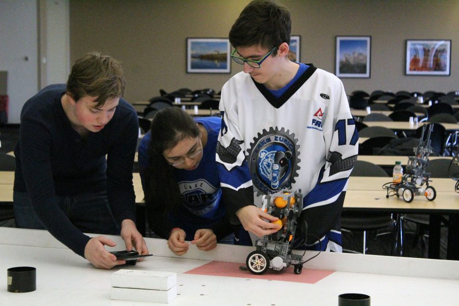 Will Stotlar, freshman, drives the robot back to home base while Olivia Reiff, sophomore, and Jason Saab, freshman, reload ping pong balls. The robot had to navigate back to the colored square home base before the team is allowed to touch it.