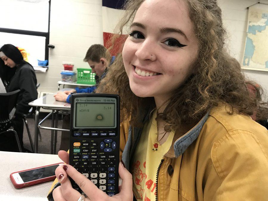 Delaney Katz, junior, uses her calculator to promote the Pi Day celebration on March 14. 