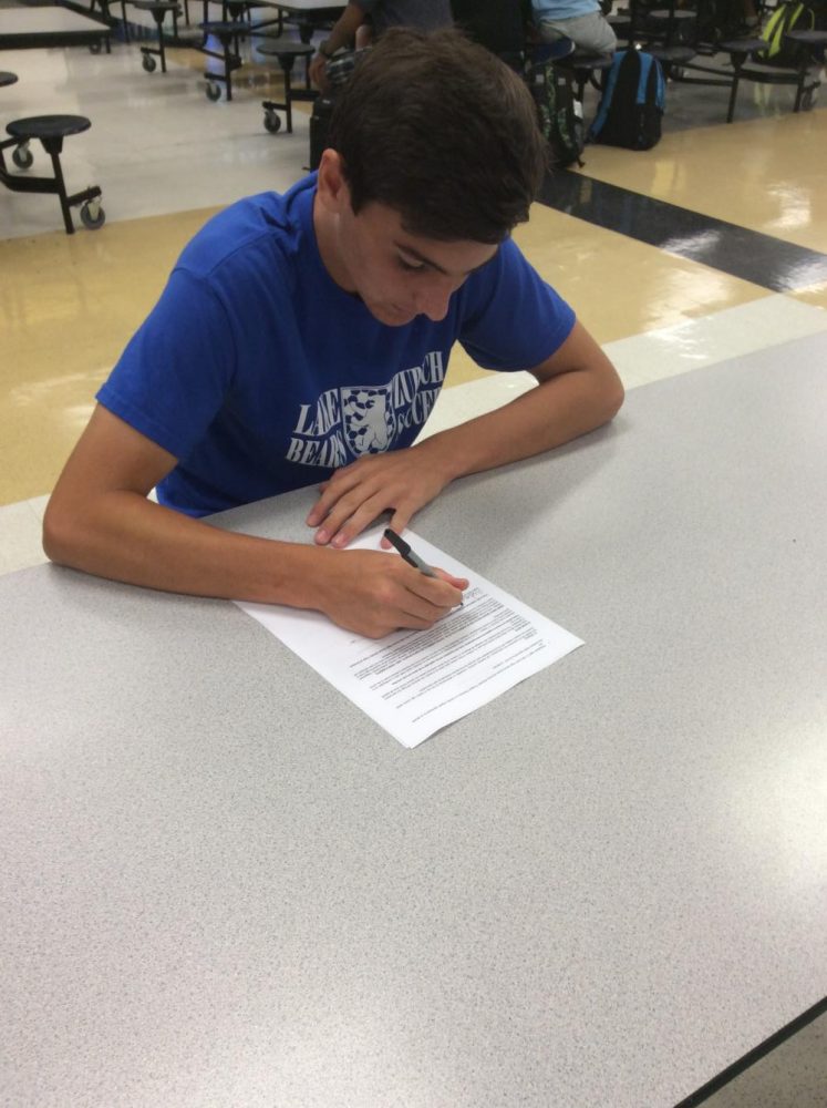 Aidan McCall, sophomore,  prepares to sign the new Code of Conduct document.