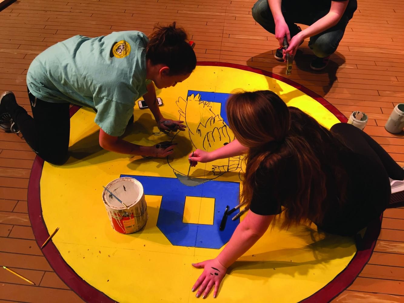 Melanie Villamarzo, senior, and Moore paint the gym floor set for last years show Spelling Bee. Alongside lighting, Moore contributes to many other aspects of production to find her creative side during technical theater.