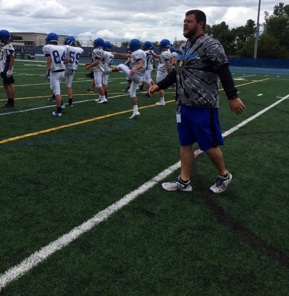 Tayler Erbach, football coach and PE teacher, performs warm ups at a football practice. 