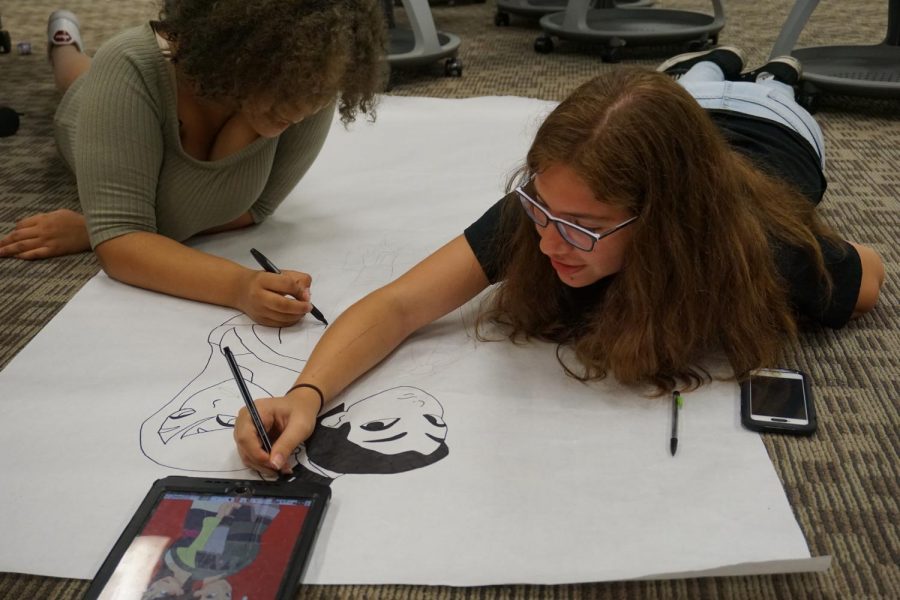 Printy Jordan (left) and Fernanda Del-Vosque (right), both freshmen members of Spectrum, sketch out a poster for the hallway.  Spectrum chose Mulan to match the homecoming this year.