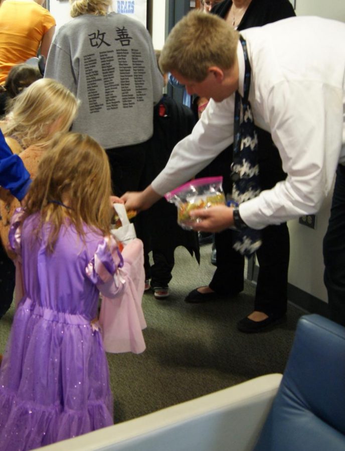 Bo Vossel, principal, places candy in the baskets of the preschoolers after they performed their Halloween song for faculty members in the main office. 