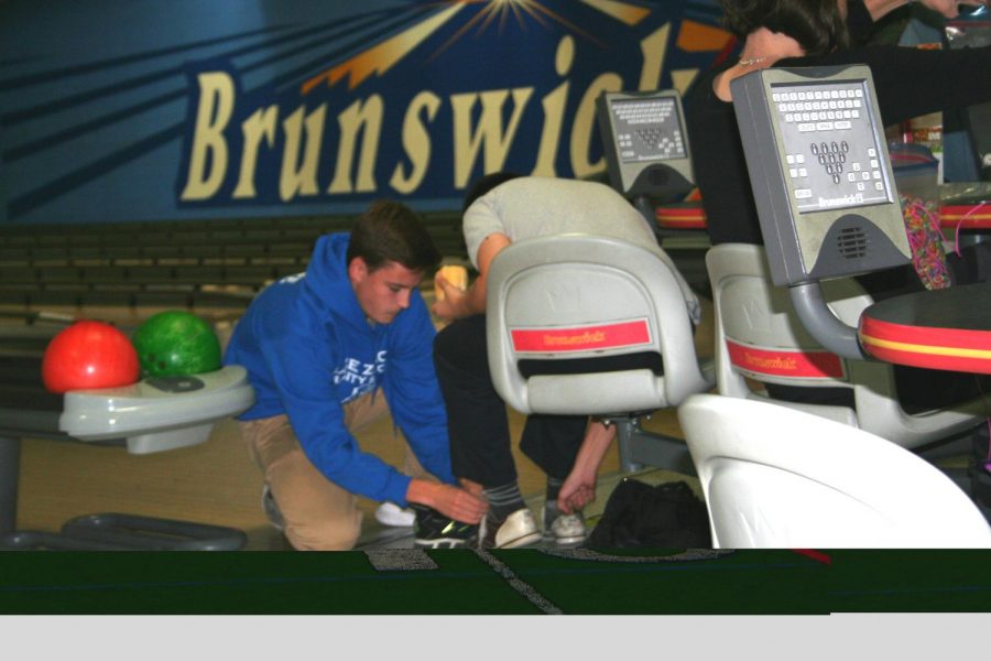 Austin Myhre, junior, helps his SNAP buddy tie his shoes as they prepare to bowl. Myhre displays the closeness SNAP buddies share, caring for each other beyond the competition of bowling.