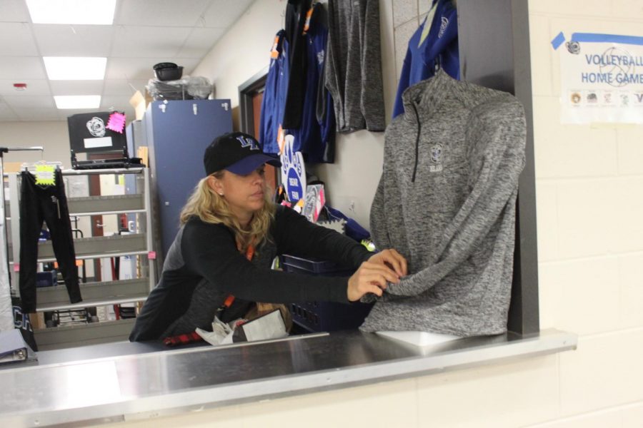 A volunteer at the school store hangs up one of the newer shirts for the students and faculty to see. 