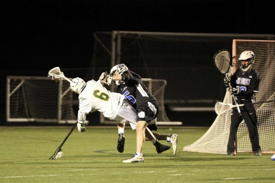 Jimmy Vaselopulos, senior, defends against an opposing player during a game. The LZHS Lacrosse Booster Club provides Vaselopulos and other players with more in-game experiences by helping pay for tournaments and matches.