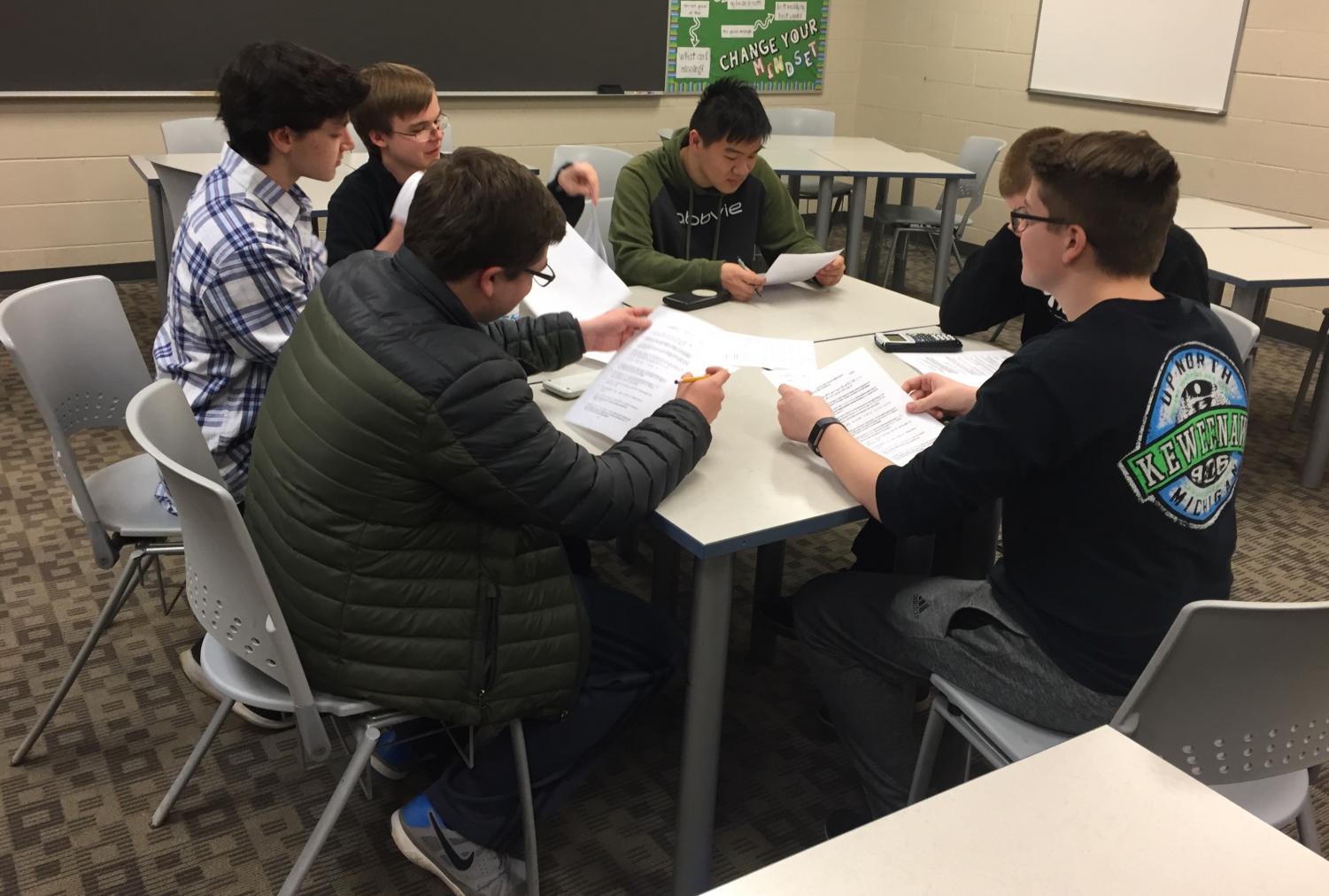 The calculator team works together during practice to solve math problems. Math team members cooperates with their teammates in order to do well in competitions.