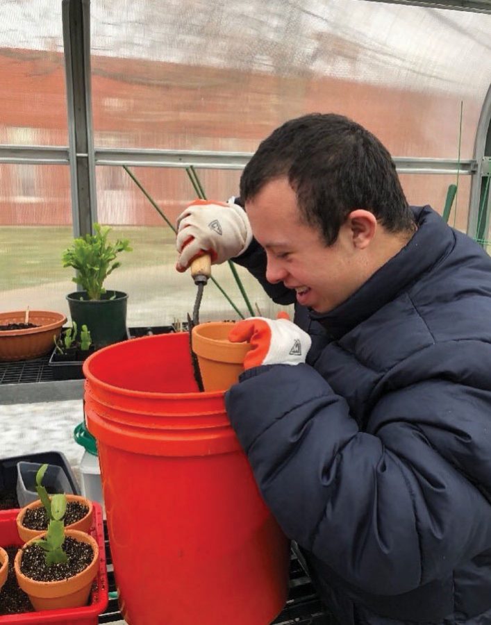 Jeffrey Murphy, transition student, adds soil to a pot to place a plant. Students work on hand-ons activities which aids in tactile learning.
