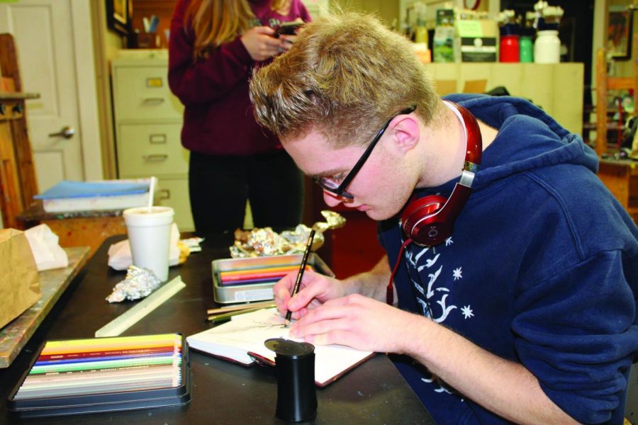 Joe Strojny, junior, draws in a story book at his art class. Strojny has been passionate about art since he was little and uses his love for others as inspiration. 