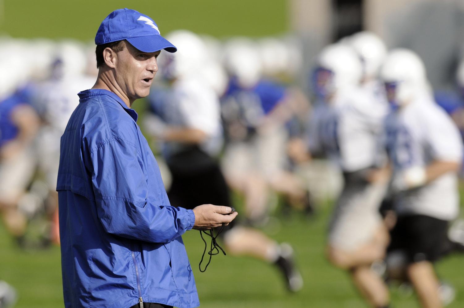 A football coach times students as they run laps on the football field. More and more outside coaches are being hired to fill coaching sports that would usually be filled by teachers due to rising expectations for educators.