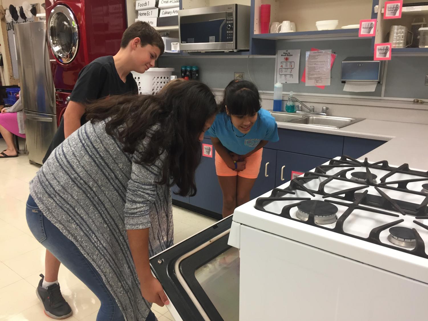 Students in the integrated Foods I class look inside the oven at their culinary creation. This is the first time the life skills students have gotten to cook in a class at school.