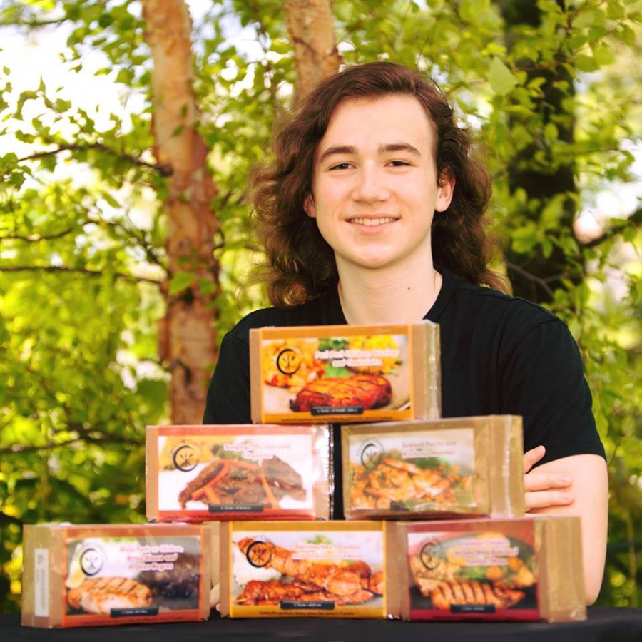 Dean Lambertsen, senior, poses with some boxes from his business. Passport Cusines is an online business where you can purchase cooking kits which include all of the pre-measured dry ingredients and spices needed to create delicious meals from around the world.