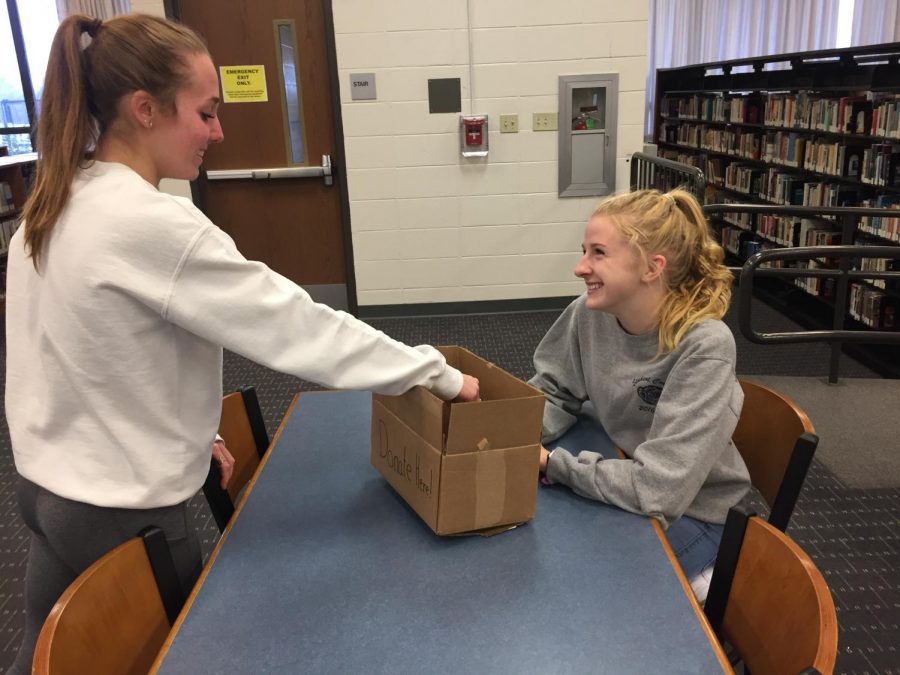 A student hands money to Jillian Baffa, senior (right), to donate to the Keep Swimming Foundation. The foundation is the chosen charity for Charity Bash this year, and clubs are already raising money in a variety of ways.