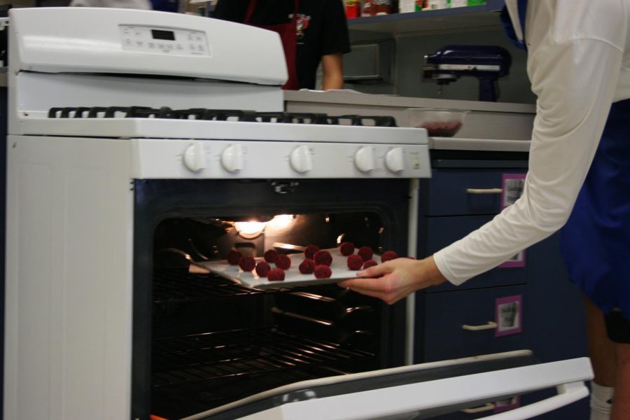 Foods 1 students slide a tray of cookies into the oven. Using kitchen appliances is just one of the skills students in Home Economics can learn.