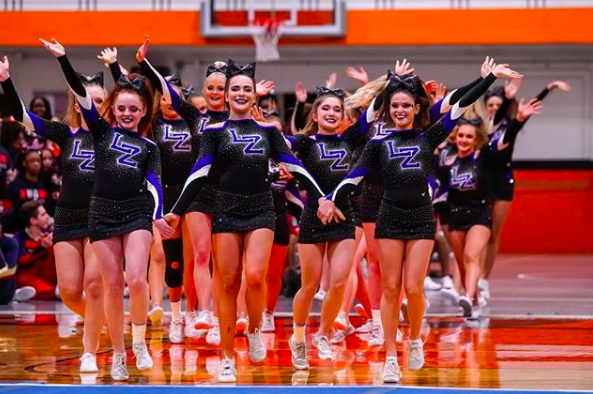 Varsity Cheerleaders wave to the crowd as they begin their routine. The team has high hopes for their upcoming competitions. 