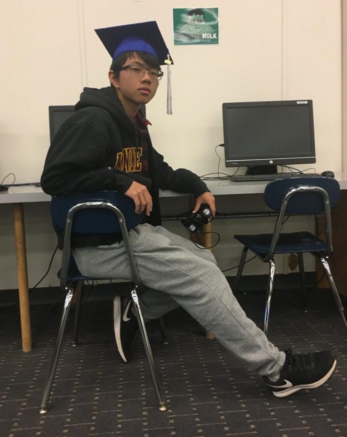 Thomas Yun is sitting in front of a computer with a gaming cube. He enjoys to play games such as DOTA, Super Smash Bros, Overwatch, and other games.