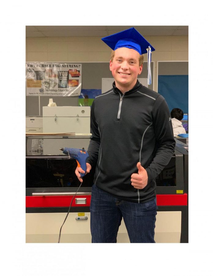 Ethan Naylor, Senior is standing in front of their robotics team laser that they use during building season. Naylor is enjoying the last moments with his equipment and teammates on the team.