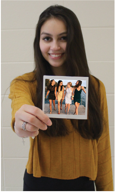 Chloe Faris, senior, holds an old polaroid out in front of her. Faris says she has had to make sacrifices in order to graduate early.