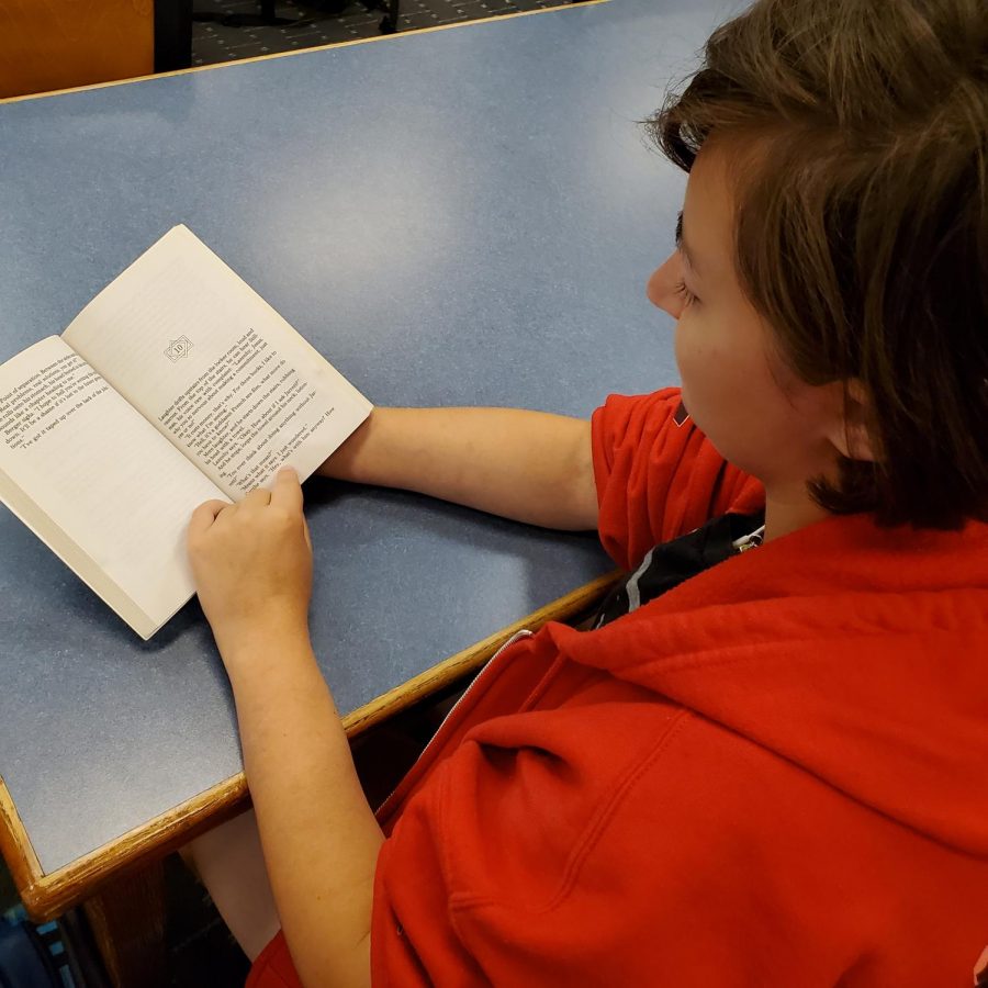 An English Honors
students reads the summer reading book required for the course before class. CP students will no longer be needing to catch up on any reading over the summer months.