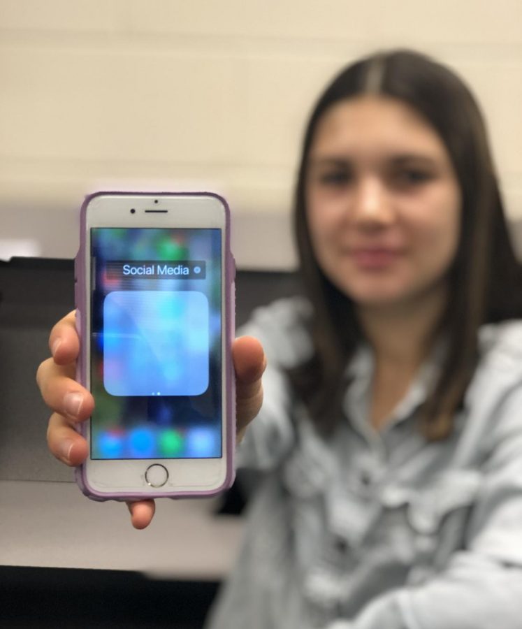 Sallie Gutt, senior, holds up an empty social media folder. Rather than communicating via social media platforms, Gutt says she prefers to talk to others in person. 