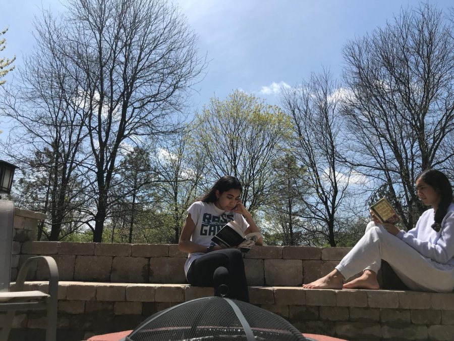 Zoya Hasan and Zara Hasan sit outside and read after a day of e-learning.