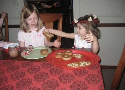 Sam Keating (right), dressed as St. Lucia at the age of four, shares a peppakakor cookie with her sister, Sarah Keating (left). The Keatings have been celebrating St. Lucia’s Day annually, ever since Keating can remember.