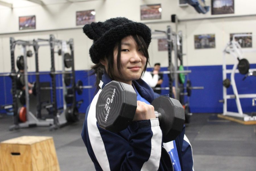 Liang+lifts+a+dumbbell+in+the+weight+room.+Liang+says+that+her+favorite+part+of+weight+training+is+the+ability+to+fit+the+course+to+her+needs.