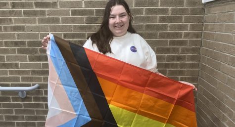 Zukowski holds up the LGBTQ+ flag that represents the queer, transgender, and African American communities to show both her pride from being a member of the LGBTQ+ community and support for other members of every community.