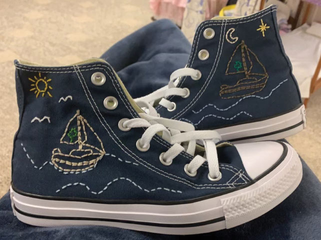 The shoes Landry embroidered in honor of her grandfather who passed away in 2020. One side of the shoes has both of their initials while the other side has a sailboat.