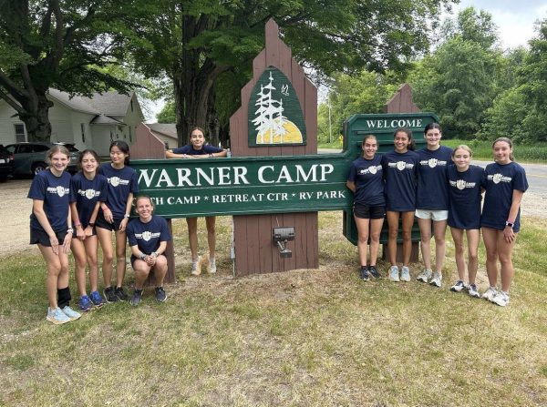 After a week of training in Michigan, Summer Fabsik (pictured fifth from the right) poses with some of the distance runners in front of the summer camp sign.