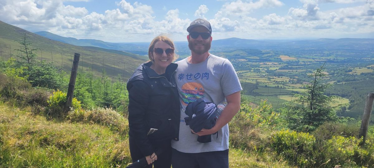 Walsh poses with his wife for a photo in front of a mountain landscape. Walsh values his family life very much and tries to spend as much time possible with his wife and his two children, 13 and 10 years old, as well as their dog, Breezy. 