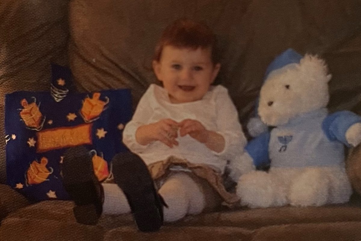 Silverman sits with a Hannukah themed bear and pillow. Silverman vividly remembers her childhood celebrations.