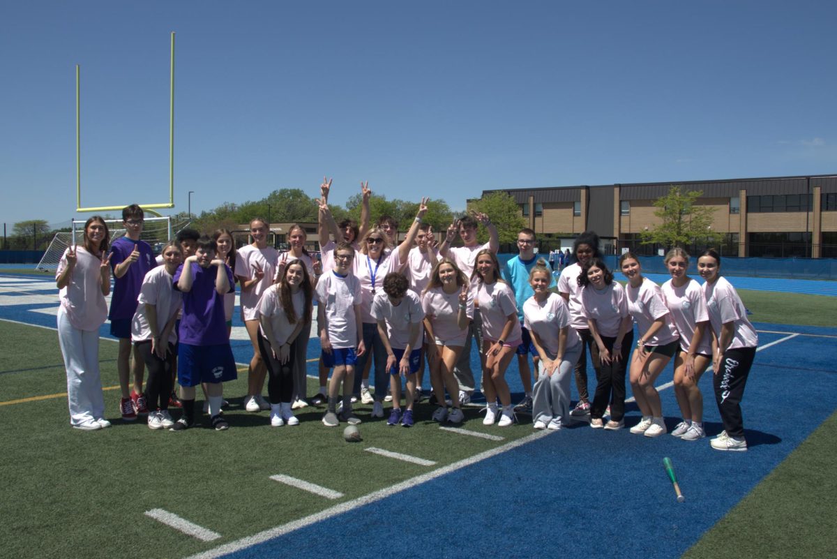 Megan Mowinski, PE teacher, poses with her Integrated PE students on the football field during class. Mowinski created the class and has been the only teacher to run it.