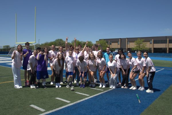 Megan Mowinski, PE teacher, poses with her Integrated PE students on the football field during class. Mowinski created the class and has been the only teacher to run it.