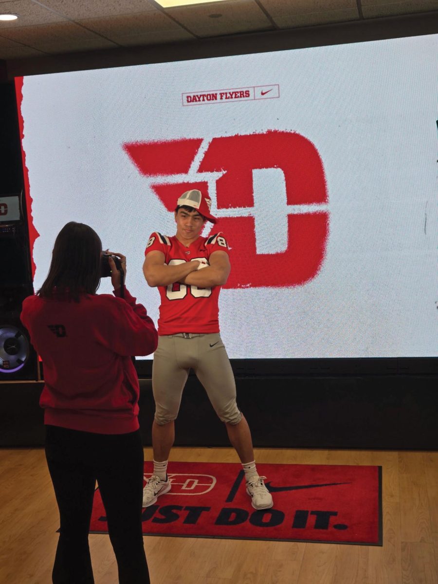 Chang poses in front of the Dayton logo. He celebrates the next step in his athletic career during a commitment event. (Photo used with permission of Chris Chang)